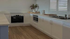 a white kitchen with a sink and a stove at Wrightaway in Coffin Bay +9 photos