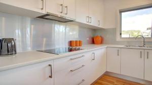 a kitchen with white cabinets and a sink and a window at Grey On The Bay in Coffin Bay