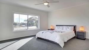 a white bedroom with a bed and a window at Grey On The Bay in Coffin Bay