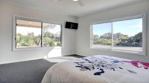 a bedroom with two windows and a bed in it at Grey On The Bay in Coffin Bay