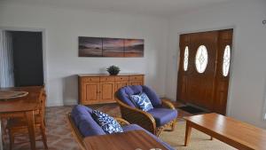 a living room with a couch and chairs and a table at Coffin Bay Retreat in Coffin Bay