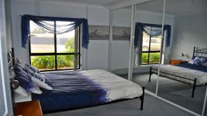 a bedroom with a bed and two windows at Coffin Bay Retreat in Coffin Bay