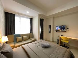 a bedroom with a bed and a couch and a desk at Genius Jakarta - Menteng Park Luxury Apartment in Jakarta