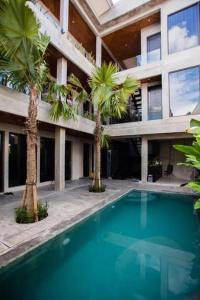 een zwembad voor een gebouw met palmbomen bij Escotel Vanili Guest House in Canggu