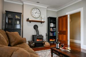 Una sala de estar con un sofá y un reloj en la pared. en Carisbrook Cottage, en Armidale