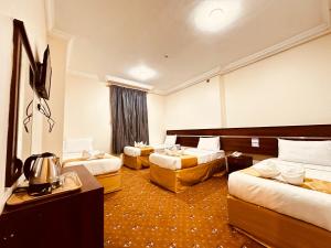 a hotel room with two beds and a television at Dhakher Plaza Hotel - Free shuttle to and from the Haram in Mecca