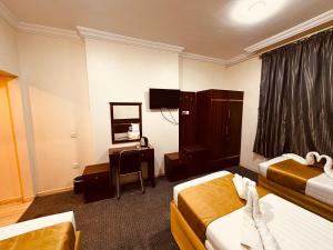 a hotel room with two beds and a desk at Dhakher Plaza Hotel - Free shuttle to and from the Haram in Mecca