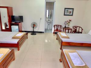 a large room with three beds and a television at Hải Yến Hotel in Dong Hoi