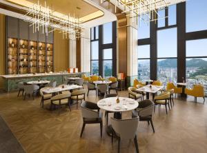 a restaurant with tables and chairs and large windows at Pullman Ambassador Seoul Eastpole in Seoul