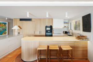 ヌーサヘッズにあるLa Mer Apartmentsのキッチン(スツールとカウンター付きのバー付)