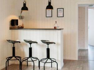a kitchen with three bar stools in front of a counter at 18 person holiday home in Væggerløse in Marielyst