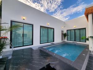 a swimming pool in a house with windows at Beloved Bliss Pool Villa Bangsaen in Chon Buri +3 photos