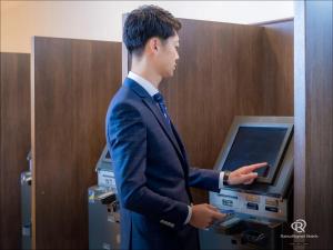 a man in a suit standing in front of a cash register at Daiwa Roynet Hotel Oita in Oita