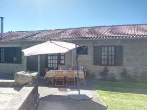 a table with an umbrella in front of a house at Quinta da Lage in Barcelos