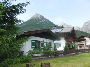 een huis met een hek en bergen op de achtergrond bij Ferienwohnung Anne in Sankt Ulrich am Pillersee