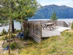 a wooden deck with a picnic table and a chair at 4 star holiday home in Stordal in Stordal