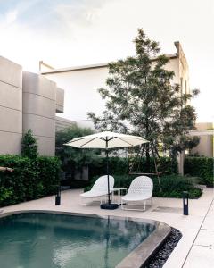 two chairs and an umbrella next to a pool at G9 HOTEL Kanchanaburi in Ban Tukkata (1) +48 photos