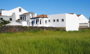 Eine Reihe weißer Häuser hinter einem grünen Feld in der Unterkunft Casa da Malta in Livramento