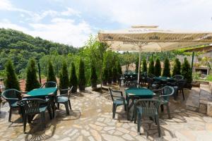 eine Terrasse mit Tischen, Stühlen und einem Sonnenschirm in der Unterkunft Hotel Terazini in Weliko Tarnowo