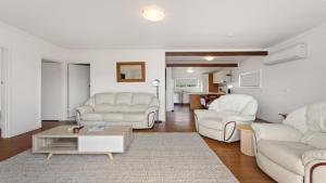 a living room with white furniture and a table at White Springs, Our Peaceful Holiday House In Coffin Bay in Coffin Bay