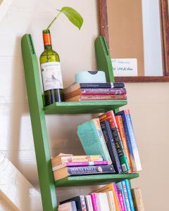 a green book shelf with a bottle of wine and books at Adella's Blue Mountain Coffee Farmstay in Kingston