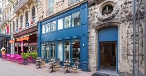 a blue building with tables and chairs on a street at Hôtel Silky by HappyCulture in Lyon