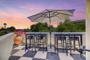 a bar with stools and an umbrella on a patio at Casa De La Vina - Boutique Suites in Downtown Santa Barbara in Santa Barbara