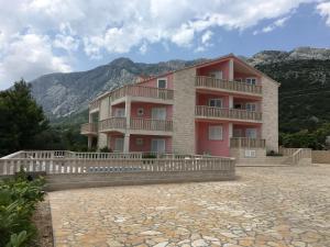 a building with a balcony and mountains in the background at Apartments Villa Jennifer in Orebić