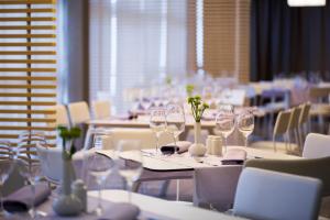 a dining room with white tables and chairs with wine glasses at Hotel Excelsior - Liburnia in Lovran