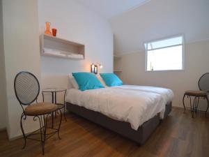 a bedroom with a bed with blue pillows and two chairs at Countryside Villa with Games in Rekken