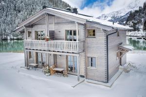 恩吉尔波登Tauerndorf Enzingerboden Ski in&out - Steinbock Lodges的一栋房子，院子里有个露台，院子被雪覆盖着。