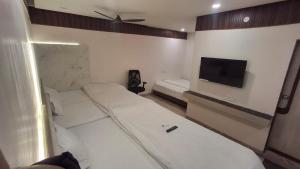 ein Schlafzimmer mit zwei Betten und einem Flachbildfernseher in der Unterkunft Hotel Kiwi Inn Reginoal Park in Indore