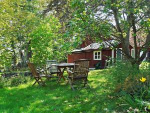 een picknicktafel en stoelen in een tuin met een rood huis bij Idyllic Family Retreat Close to the Sea in Ronneby