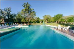 a swimming pool with blue water and white chairs at Hotel Radio in Valle Hermoso