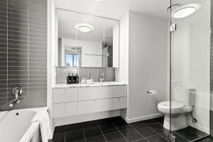 a white bathroom with a sink and a toilet at Docklands Harbour View 3BR with Free Parking in Melbourne +26 photos
