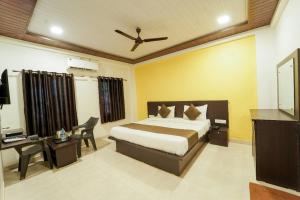 a bedroom with a bed and a desk and a television at Hotel Raaya Regency in Mahabaleshwar
