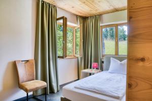 a bedroom with a bed and a chair and windows at Gästehaus Alpina in Krün