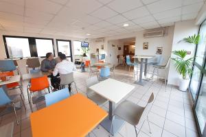 deux personnes assises dans une pièce avec des tables et des chaises dans l'établissement Fasthôtel Clermont sud, à Aubière