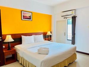 a bedroom with a large bed with a yellow wall at Sirimathani Hotel in Ban Hua Fai