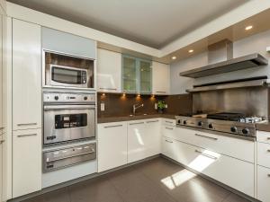 une cuisine avec des armoires blanches et des appareils en acier inoxydable dans l'établissement Villa Stay with Pool & Sauna, à Coxyde