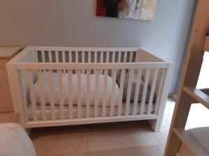 - un lit bébé blanc dans une chambre avec un mur dans l'établissement Villa Stay with Pool & Sauna, à Coxyde