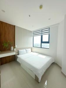 une chambre blanche avec un grand lit avec une fenêtre dans l'établissement Hue Charm Apartment -Nera Garden, à Thôn Văn Dương