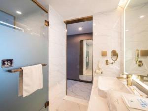 a white bathroom with a tub and a sink at 7 Days Inn Huizhou Daya Bay Wanda Plaza in Huizhou +106 photos