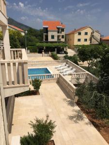 a swimming pool with lounge chairs and a house at Apartments Villa Jennifer in Orebić