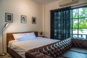 a bed with a leather couch in a bedroom with a window at Photharam126 Resort in Ban Khlong Ta Khot