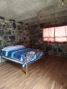 a bedroom with a bed in a stone wall at Nasaka jacala in Cuetzalán del Progreso