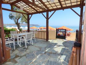 a patio with a table and chairs on the beach at Camelia Studios & Apartments in Stalos