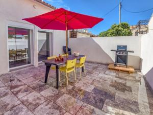 Un patio con una mesa y sillas y una sombrilla. en Holiday Home La Seyne near Beaches, en La Seyne-sur-Mer