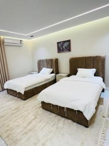 two beds in a room with white walls and wood floors at Neem Premium Villa in Al Jubayl +29 photos