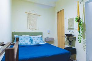 a bedroom with a blue bed and a wooden table at Suite dos Anjos com Cozinha 150m da Praia in Arraial do Cabo